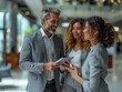 © Fridocha - Three professionals engaged in a discussion, sharing a tablet in a modern office setting.