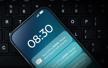 otp message notification on mobile screen with laptop in the backdrop. one time password for secure 