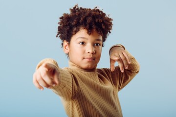 Enthusiastic young african american boy gesturing with confidence against a vibrant blue background in casual attire