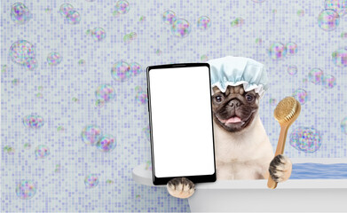 Leinwandbilder - Funny Mastiff puppy wearing shower cap holds shower brush, takes the bath shows big smartphone with white blank screen in it paw. Empty space for text