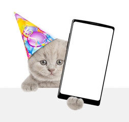 Aufkleber - Cute tiny kitten wearing party cap shows big smartphone with blank screen above empty white banner. isolated on white background