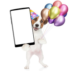 Poster - Happy jack russell terrier puppy wearing party cap, holding balloons and  big smartphone with white blank screen in it paw. isolated on white background