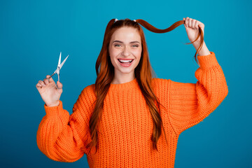 Photo of shiny attractive lady dressed knitted pullover holding scissors ponytails empty space isolated blue color background