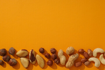 Wall Mural - Assortment of different nuts on an orange background