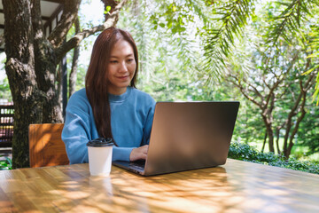 Wall Mural - portrait image of a woman working and typing on laptop computer in the outdoors