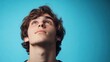 © Lifestyle Images - A young man with brown hair and a smile on his face is looking up at the sky