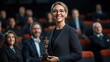 © AnuStudio - Smiling woman holding an award trophy in a formal event, surrounded by a professional audience.