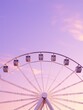 © lolya1988 - A vibrant and colorful Ferris wheel set against the backdrop of a beautiful sunset at the fairground. Light purple pink lavender sky.