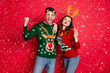 © deagreez - Portrait of crazy flirty two family people wife husband brown hair win wear deer antler costume eyeglasses seasonal christmas tree design clothes denim jeans isolated over red color background