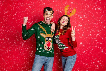 Portrait of crazy flirty two family people wife husband brown hair win wear deer antler costume eyeglasses seasonal christmas tree design clothes denim jeans isolated over red color background