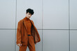 © SHOTPRIME STUDIO - Stylish young man in a brown outfit posing confidently against a minimalist gray wall