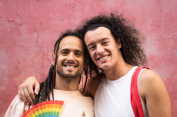 Portrait of gay couple smiling and hugging together isolated on purple background