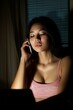 © Generative ART - Focused asian businesswoman working late and speaking on smartphone