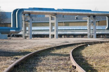 railway track on wooden sleepers close-up in the background a pipeline and a plant