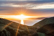 © Cavan Images - Beautiful sunset vista over ocean and green mountains