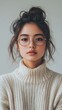 © Sasa Visual - A young woman in round glasses and a cozy sweater flaunts her style in a minimal setting