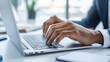 © Piyapat - Hands typing on a laptop in a modern office setting.