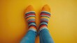 © Vii - A person wearing striped socks and jeans on a yellow surface