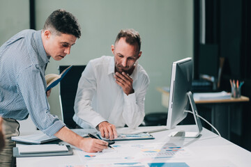 Two businessmen working together Analyze financial reports with charts and graphs while using the calculator to calculate budget, income, taxes, business growth. Startup business idea.