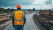 © night - A construction worker in a hard hat and safety vest stands on a building site.