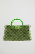 © Vadym - A rectangular bag made of transparent green beads with a bright rounded handle. An elegant and modern accessory presented on a neutral background that emphasizes its lightness and grace.