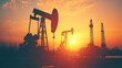 © Art.disini - Silhouetted oil pump jack and drilling rig against a sunset backdrop.