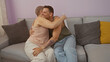 © Krakenimages.com - Mother and adult son embracing warmly on a cozy couch in a brightly lit living room showing love and family connection