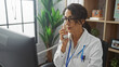 © Krakenimages.com - Mature woman doctor in white coat talking on phone in her office with computer and plants reflecting a professional indoor setting.