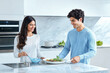 © ADDICTIVE STOCK CORE - Young couple cooking together in bright kitchen. Generative AI