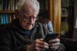 © ivlianna - An elderly person struggling to use a smartphone, feeling frustrated and overwhelmed.An man sits comfortably in a chair, closely viewing his phone
