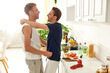 © Bliss - A loving gay couple embraces while preparing vibrant vegetables for a fresh salad in their stylish kitchen.