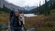 © Viktoriia Kan - A young woman with a joyful smile carries her corgi dog in a hiking backpack while enjoying a warm autumn day by a forest lake surrounded by colorful foliage