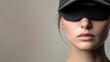 © WINGGOD - Woman wearing a cap tilted to cover one eye, with a serious expression, standing against a neutral background