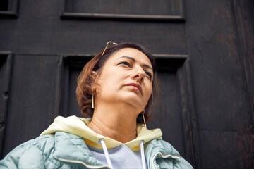 Confident woman in casual attire standing against a dark wooden door