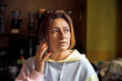 © Ktn - Woman engaged in thoughtful phone conversation indoors