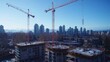 © Natchooda - Tower cranes lifting beams at a modern construction site with cityscape in the background, showing urban development