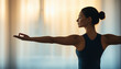 © Naphol - A woman practicing yoga with arms extended, embodying peace and balance against a soft, blurred background.