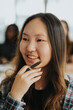 © Maskot - Smiling teenage girl holding pen with hand on chin at high school
