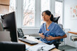 © Maskot - Female medical expert sitting on chair and doing online consultation on video call through computer at clinic