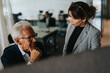 © Maskot - Senior businessman discussing strategy with female colleague in office