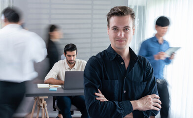 Confidence and happy smiling businessman portrait with blur motion background of his colleague and business team working in office. Office worker teamwork and positive workplace concept. Prudent