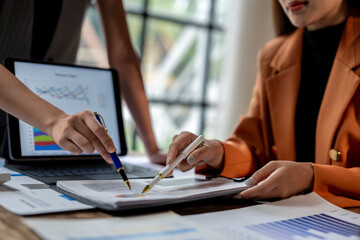 two businesswomen are having a working session analyzing financial charts on a report