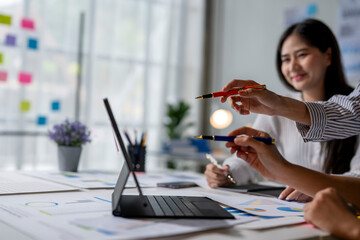 Wall Mural - A woman is pointing at a laptop screen with a red pen in her hand