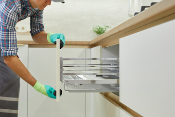 An experienced craftsman assembles furniture in a modern kitchen. Installation of drawers with telescopic guides.