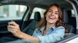 © Alex Pios - Excited European woman sitting in car salon, happy owner holding car key looking back at camera and smiling. Car insurance concept