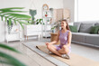 © Pixel-Shot - Sporty young woman meditating on mat at home