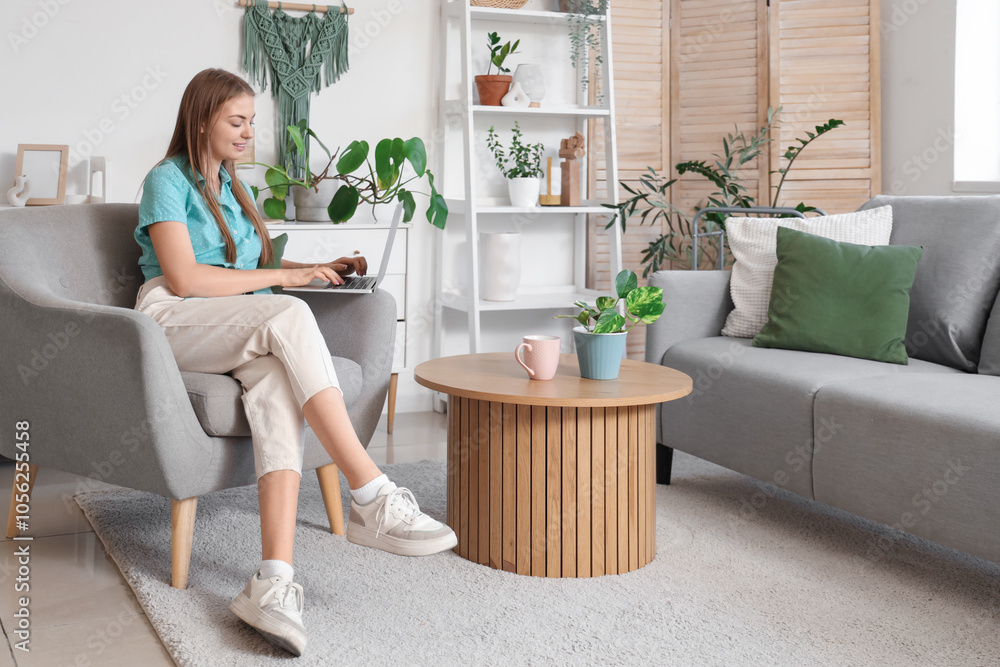 Young woman using laptop in armchair at home