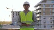 © volha_r - Man construction site engineer holding tablet and wearing hard hat and safety vest with a sunrise at the background in early morning