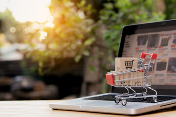 Shopping online. cardboard box with a shopping cart logo in a trolley on laptop keyboard. Shopping service on The online web. offers home delivery