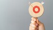 © Tipakorn - Hand holding target symbol with arrows, representing goals and focus